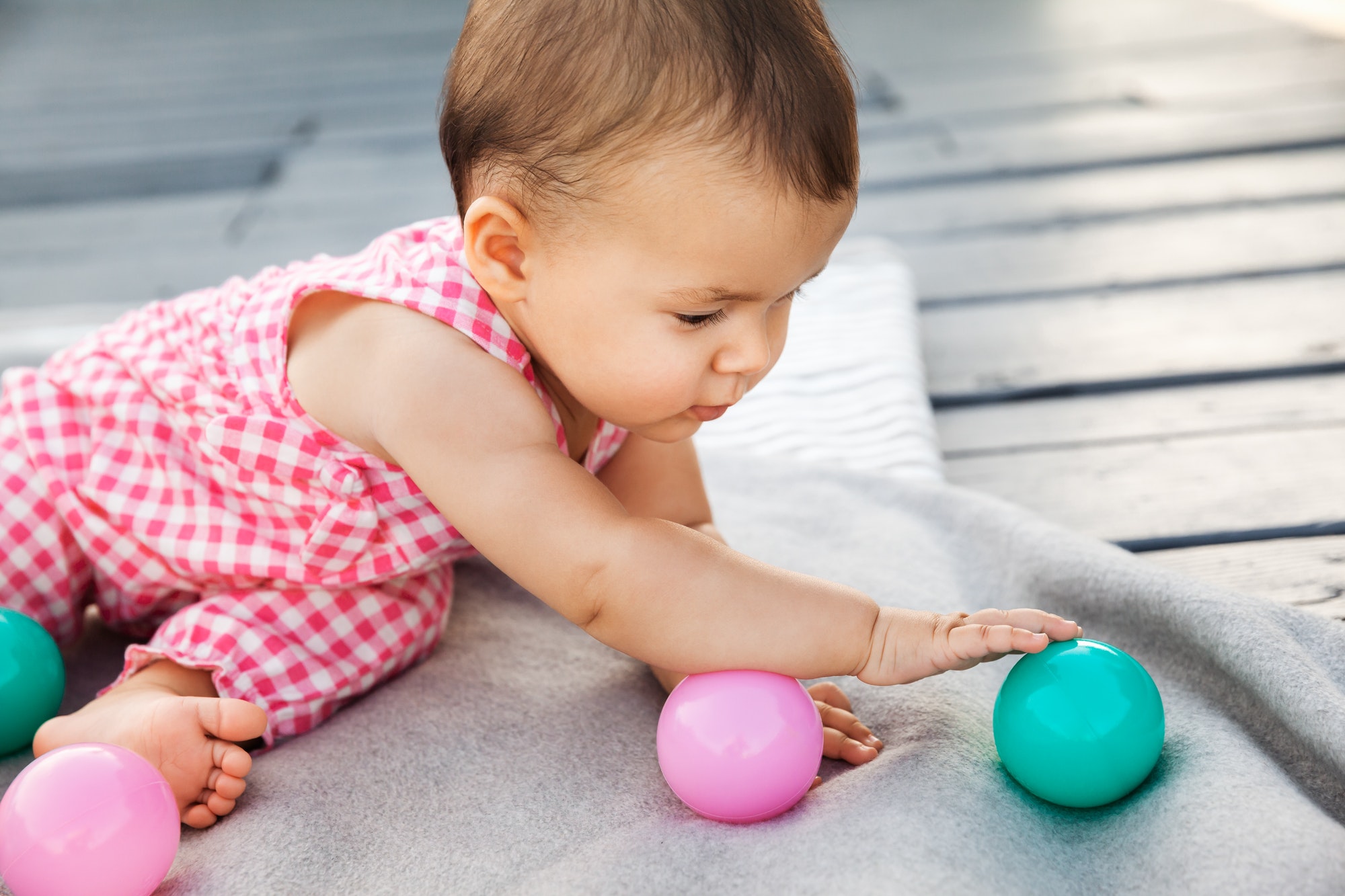 Infant baby girl playing with colorful balls