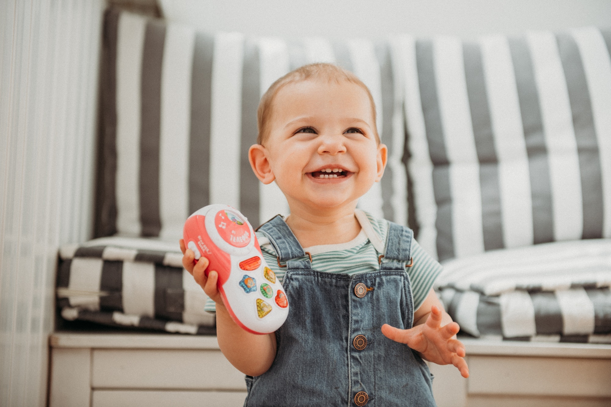 Infant girl holding toy phone and laughing emotional lifestyle portrait